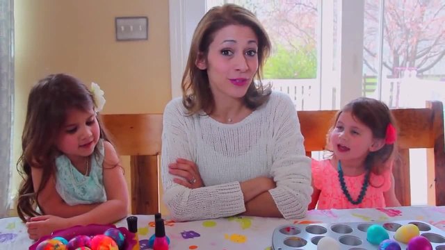 Млада майка с дъщерите си показва как се боядисват великденски яйца с лак за нокти