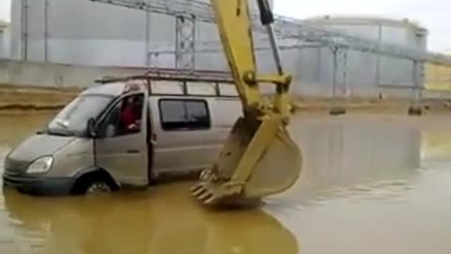 Изобретателен багерист помага на шофьор със закъсал бус в наводнена улица