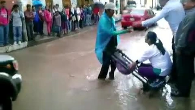 Човек превозва хора от наводнена улица с количка