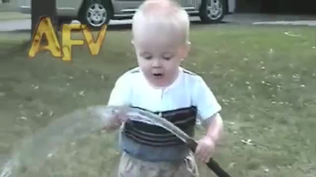 Жадно бебе се опитва да пие вода от градинския маркуч