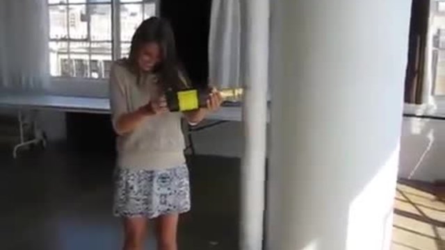 Момиче отваря фалшива бутилка шампанско .