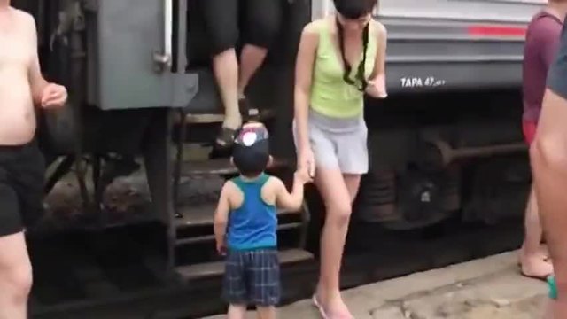 Момченце поздравява хората слизащи от влака за добре дошли